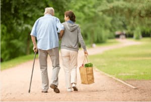 badante che accompagna un anziano a fare una passeggiata